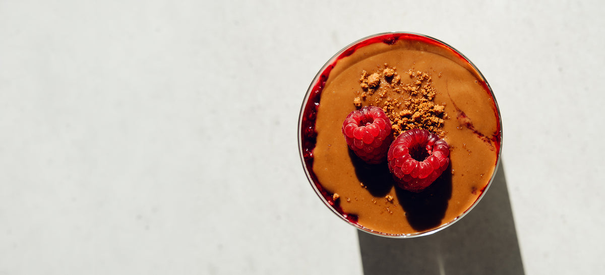 Birds eye view of a jar of Made Monday overnight oats with a caramel topping, raspberries and crumbled biscuit.
